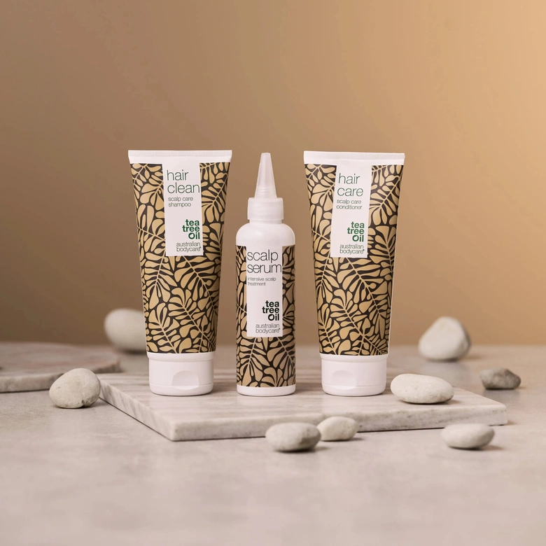 Tři lahvičky péče o vlasy značky Tea Tree Oil na mramoru.