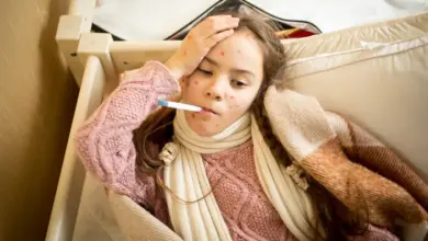 Dívka s neštovicemi leží v posteli, má horečku a vyrážku na kůži.