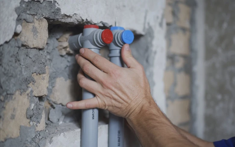 Ruční instalace nových vodovodních potrubí v nezhotovené zdi