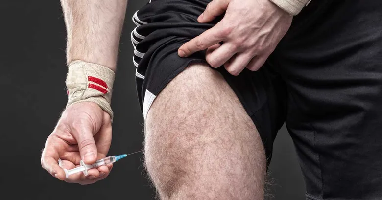 Muž podává injekci testosteronu do stehna pomocí špičky.