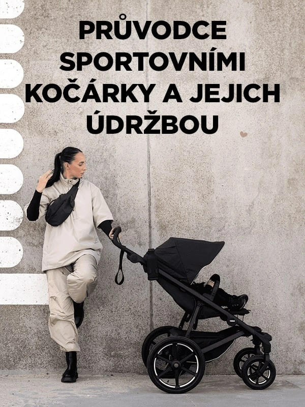 Žena stojí vedle černého terénního kočárku u betonové zdi.