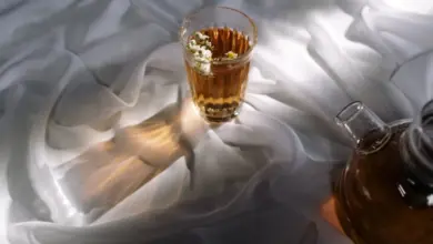 Sklenička s čajem a květinami na bílém podkladu