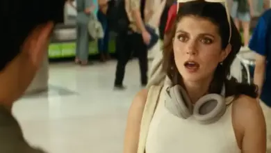 Žena s sluchátky a brýlemi na hlavě v davu lidí.