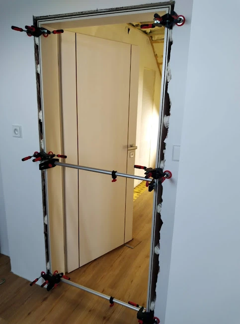 Montáž zárubně pomocí spon pro správné vycentrování rámu.