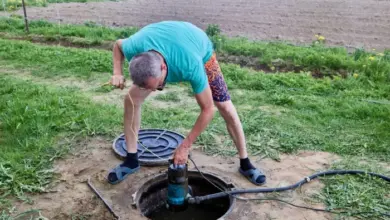 Muž instaluje čerpadlo do studny v zahradě.
