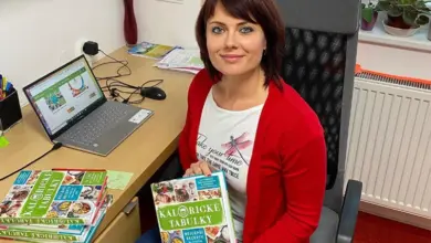 Žena drží knihu o kaloriích sedící u pracovního stolu.
