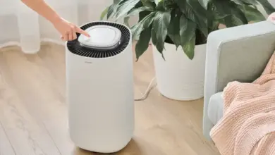 Bílý odvlhčovač vzduchu s rukou tlačící na ovládací panel.