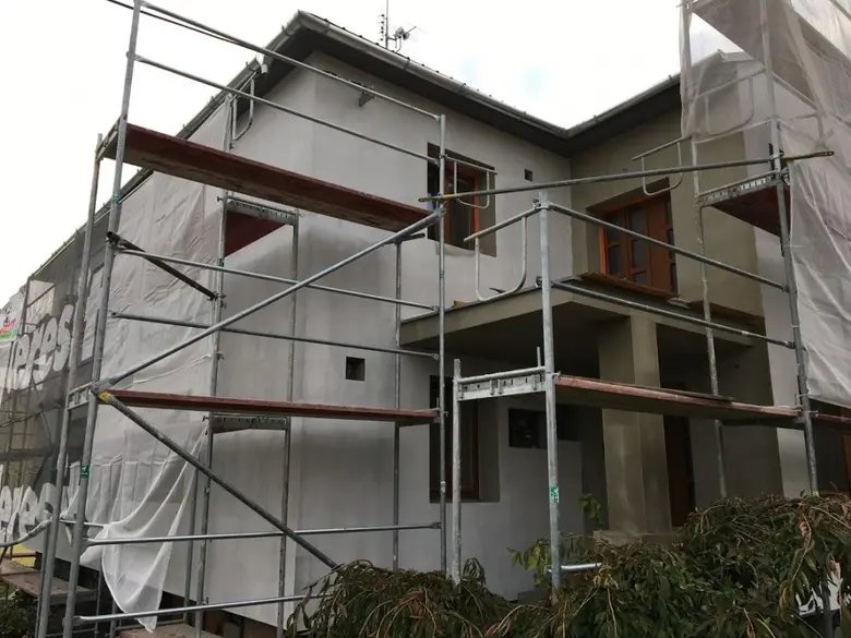 Dům s fasádou zateplovacími opěrnými konstrukcemi a plachtami.